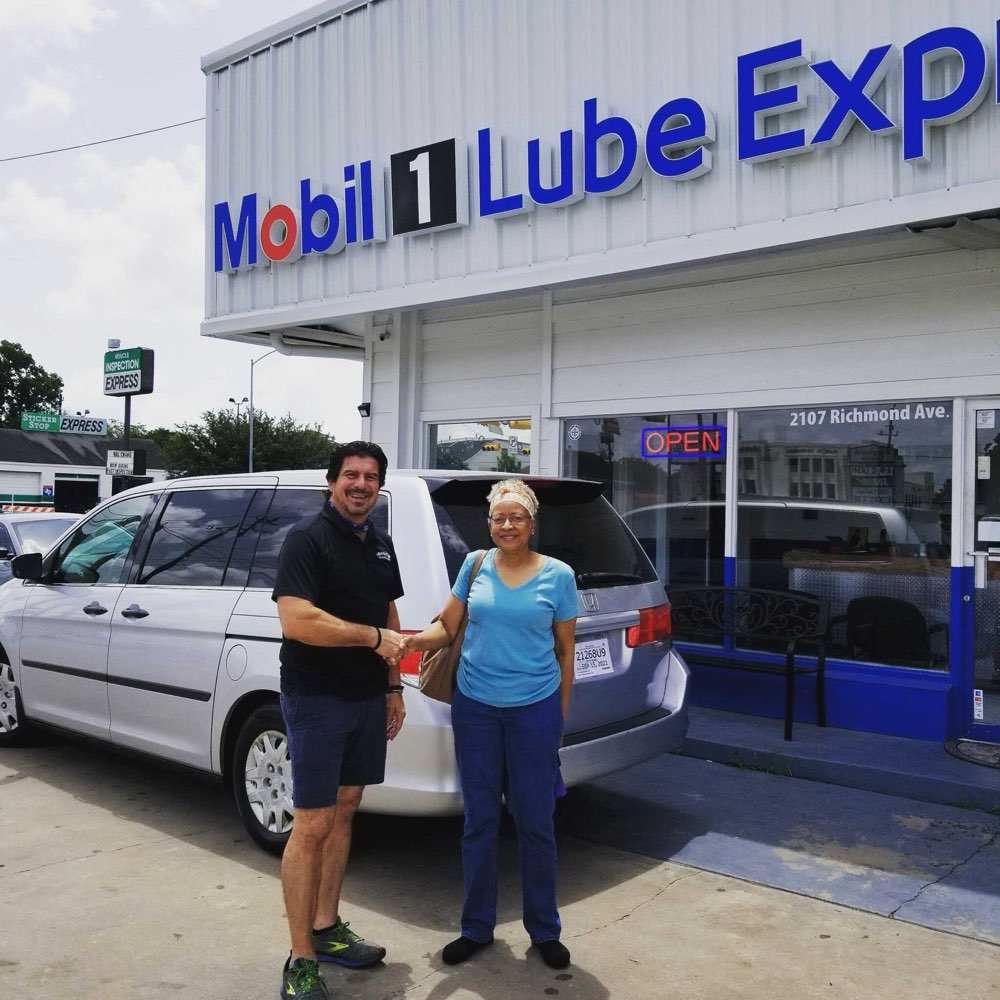 Frankie shaking hands with a customer beside her minivan outside the shop